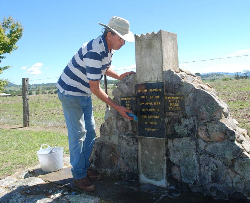 Neighbour John Brown cleans the crash site memorial in preparation for Sunday's ceremony.