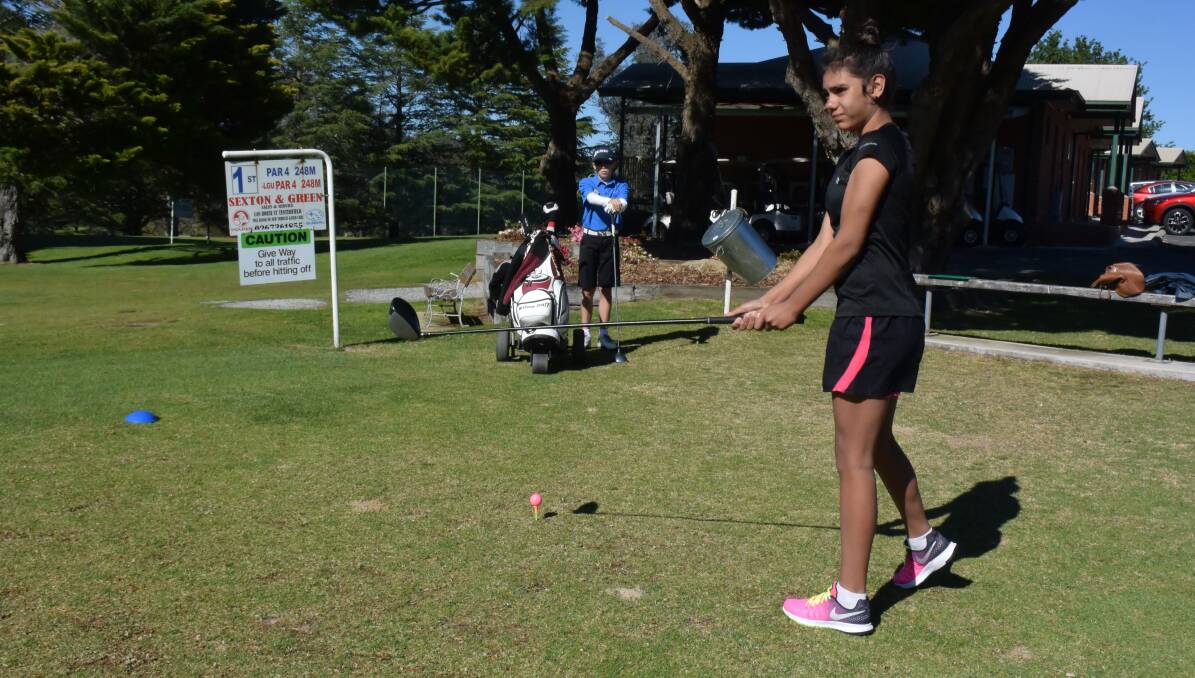 TEEING OFF: Thirteen-year-old Mikahla Cutmore of Tenterfield takes a practice swing as 11 year-old Luke Devney of Moree awaits his turn.