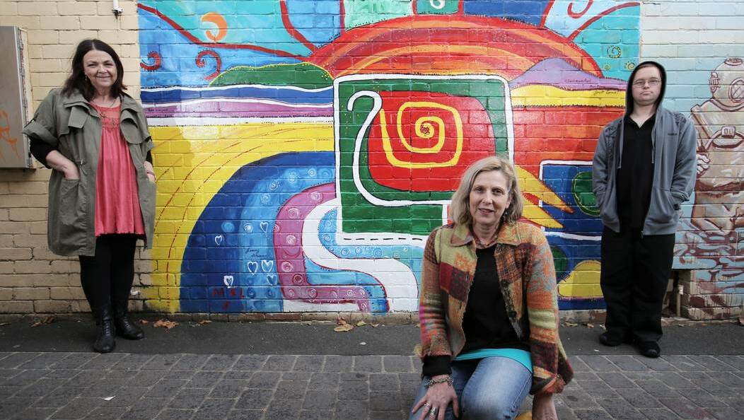 Artists Jenny Altmann (left), Gayle Hill Clark and Alex Rees defied the gloomy skies to put the finishing touches to their colourful artwork in a laneway to the Ozone car park. Picture: ROB GUNSTONE, The Standard - Warrnambool