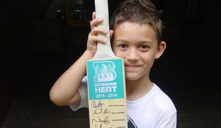 AUTOGRAPHS: Ethan Green with the cricket bat signed by the Brisbane Heat team.