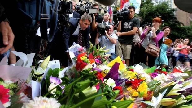 NSW Premier Mike Baird joins fellow mourners in laying flowers in Martin Place today. Photo courtesy of SMH.