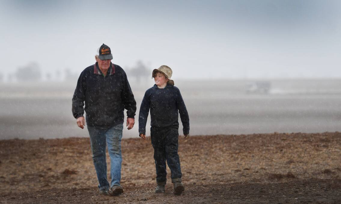 Hit and miss: Kevin Tongue and his grandson Blake enjoy a walk in the rain on their Loomberah property, although not everyone was so lucky.  Photo: Gareth Gardner