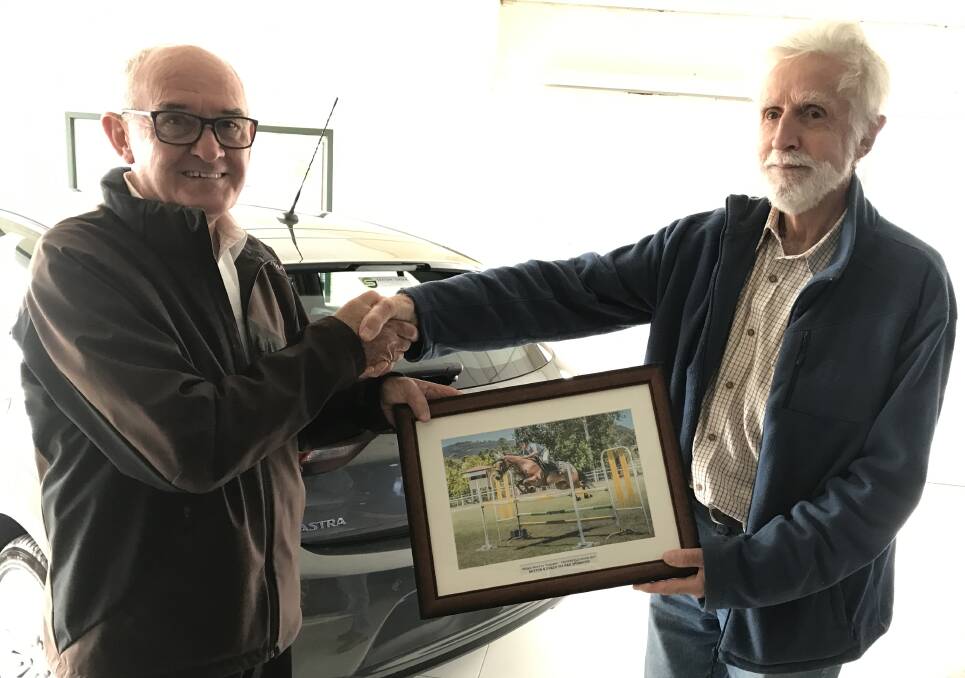 Sexton & Green's Graeme Rossington receives a photograph of William Wood on 'Cupcake' jumping at the 2016 Show from show jumping steward Noel Cossins.