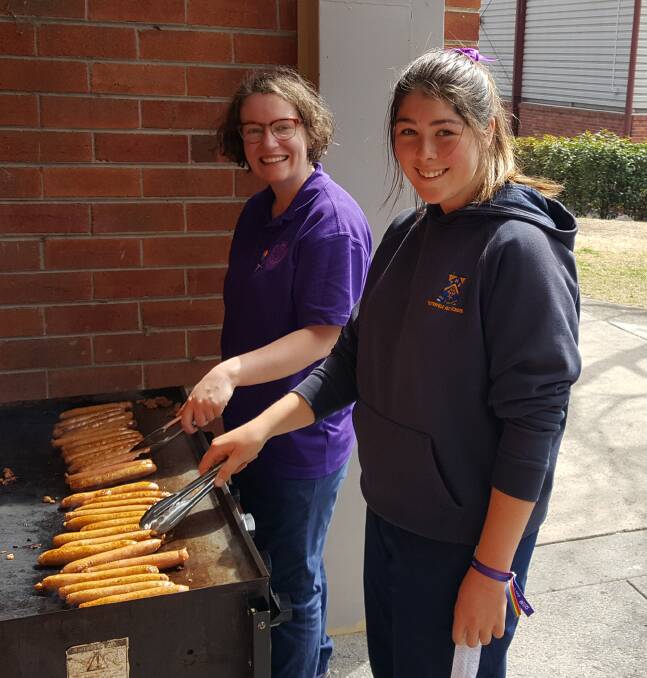 Megan Rivett and Courtney Watt attend to the snags at the Wear It Purple barbecue.