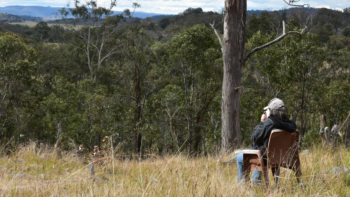 Leeza Wishart atop a hillside on her 'Optus chair' to seek a signal, although she said it's a bleak job when the cold westerlies blow.