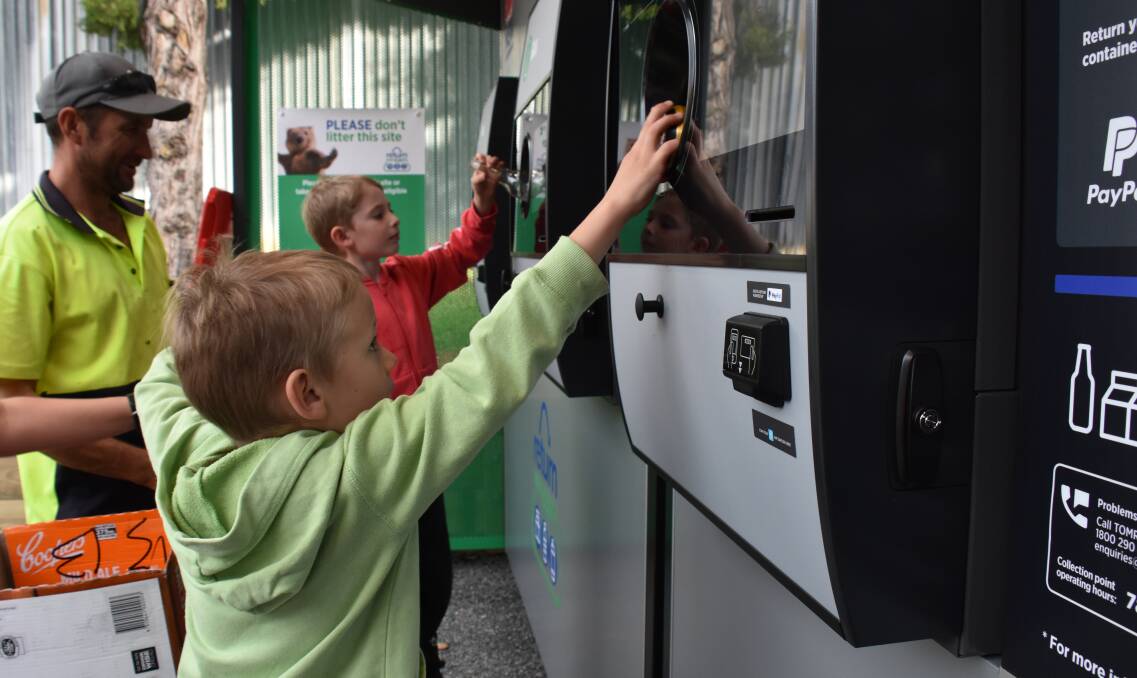 Reid (in foreground) and Nate Lockwood feed the new reverse vending machine, under the supervision of dad Lindsey.