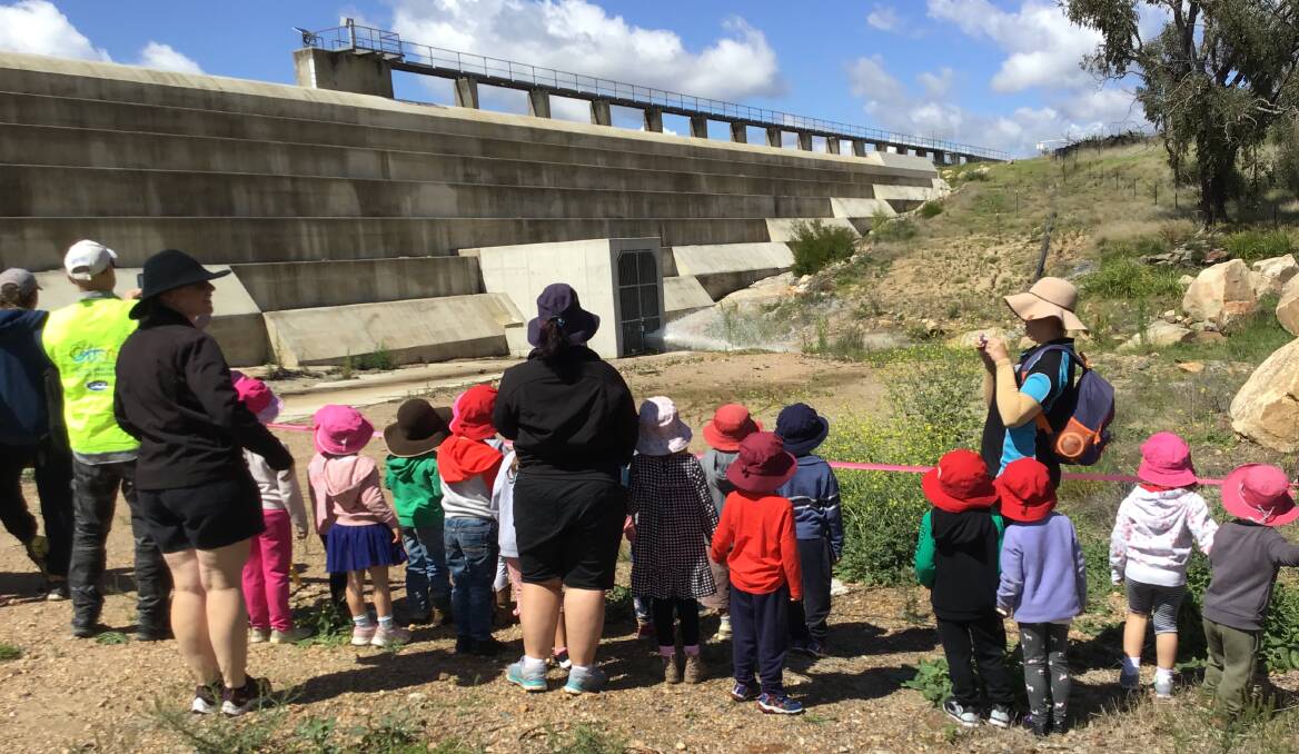 Tenterfield Preschool students watch the valve in the wall of the Tenterfield Dam opening, before checking on the welfare of fish downstream.