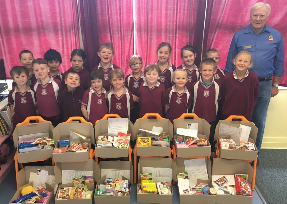President RSL Wallangarra Dennis Pollard with the Wallangarra State School Prep/1 students and the care packages destined for military personnel.