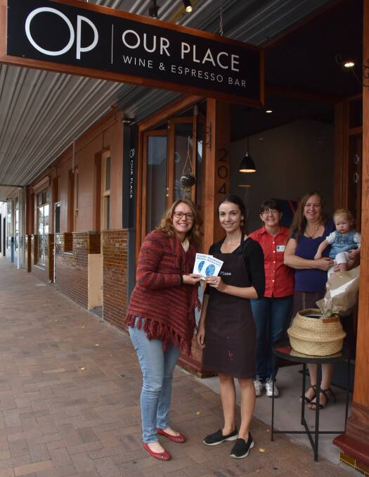 Rebecca Everett presents Our Place's Matilde Newsome with 'breastfeeding friendly' stickers for the newly-accredited establishment. Fellow Granite Belt Breastfeeding Association members Cara Hall and Leah Furness (holding Martha) look on.