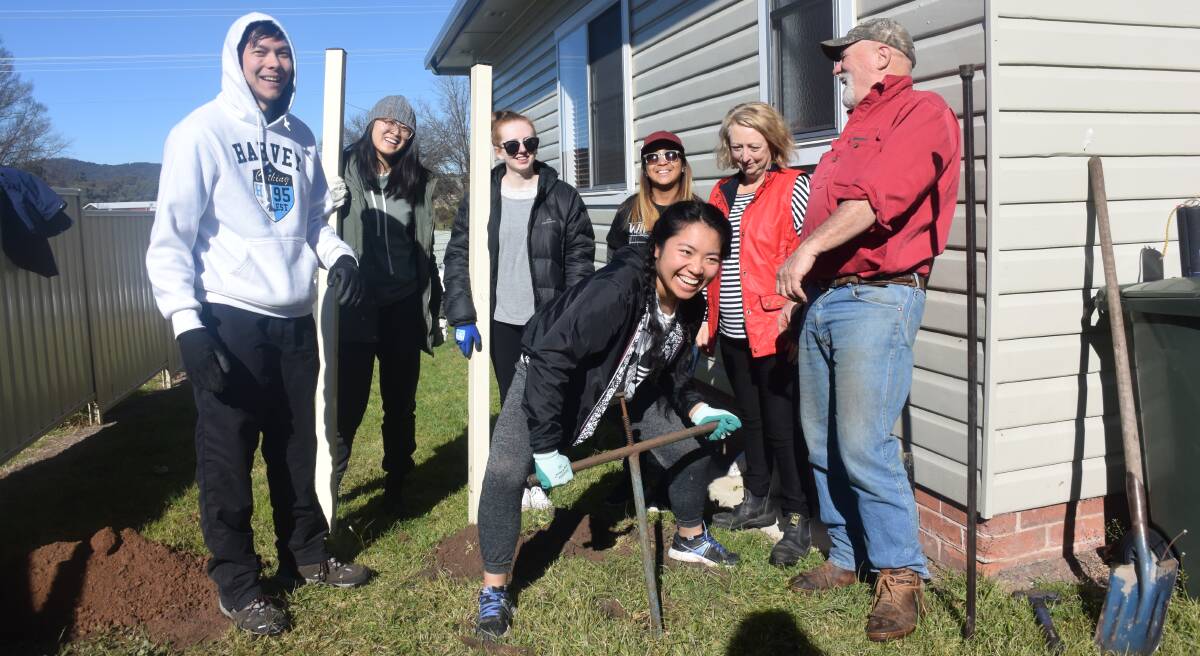 Michelle Chung does the hard yards digging a hole for the new side fence at Challenge Services, under the supervision of (from left) Dominic Lee, Steffi Chiang, Amber Smyth, Wihyn Canascal, Jim Hamilton and Sue Griffiths.