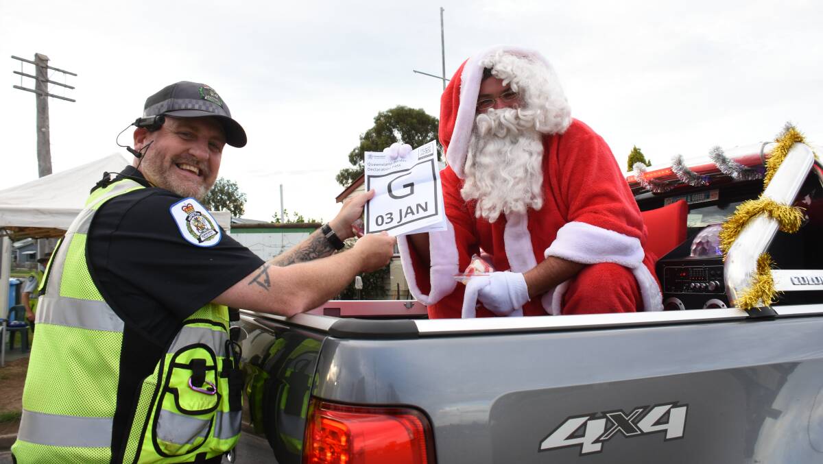 Santa travels on a General pass (not Logisitics?): Senior Transport Inspector Drew Bennedick checks that Santa has a legit border pass as he crosses back into Queensland at Wallangarra. Photo: Donna Ward.
