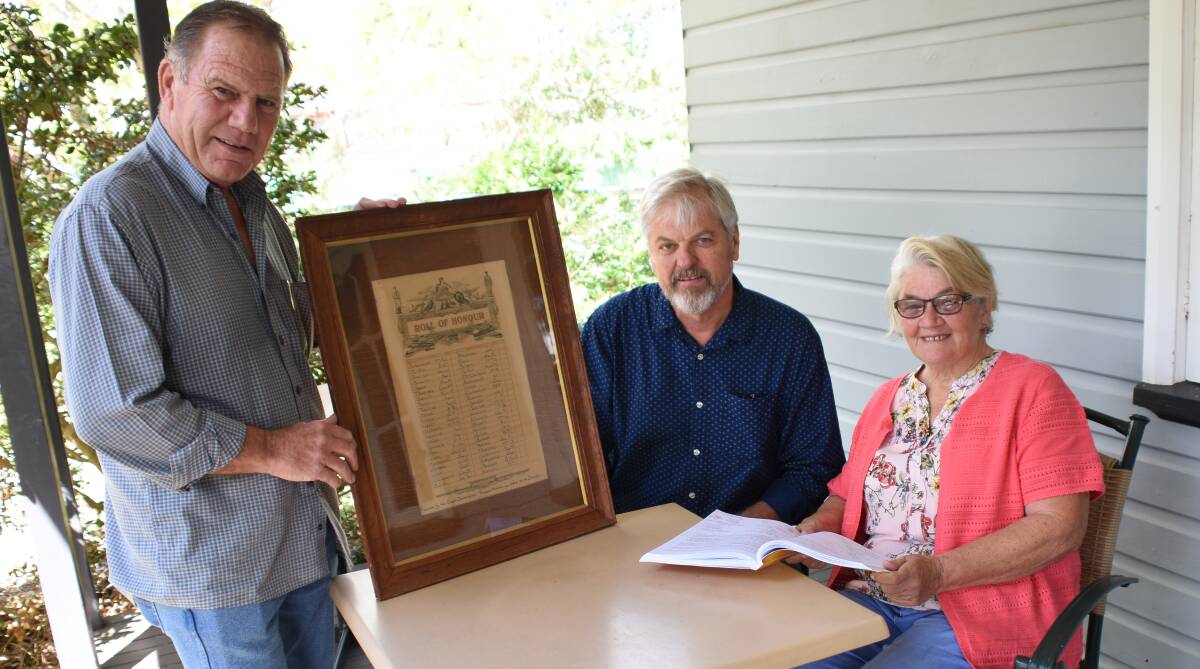 ANZAC Centenary Committee members David Stewart, Peter Reid and Jan Friar put the finishing touches to the draft before the initial print run. Mr Stewart holds an honour board of the East Tenterfield Progress Association, that was unearthed in a council storage room.