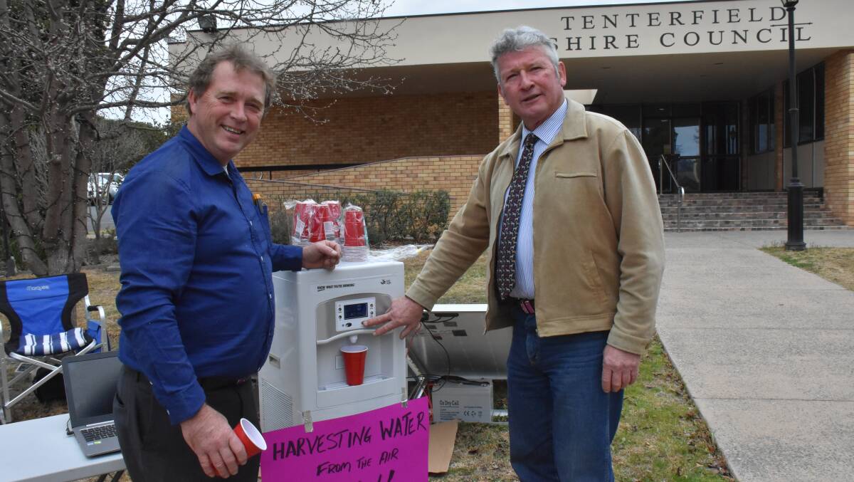 Richard Kowalski offers mayor Peter Petty a taste test of the World Environment Systems' atmospheric water harvester.