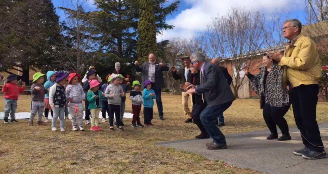 Mayor Peter Petty (in suit) gets down to some dancing in Bruxner Park in the hope of bringing on rain, aided by some much cuter rain dancers from Tenterfield Child Care Centre.