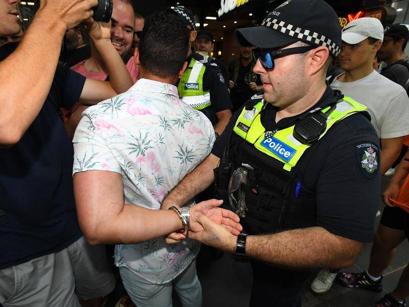 Far-right figure Avi Yemini was led away from Melbourne's Invasion Day marchers by police.