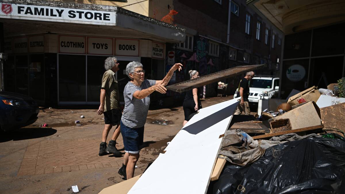 A woman throws away flood-damaged goods from a business in Lismore on Thursday. Picture: Getty Images